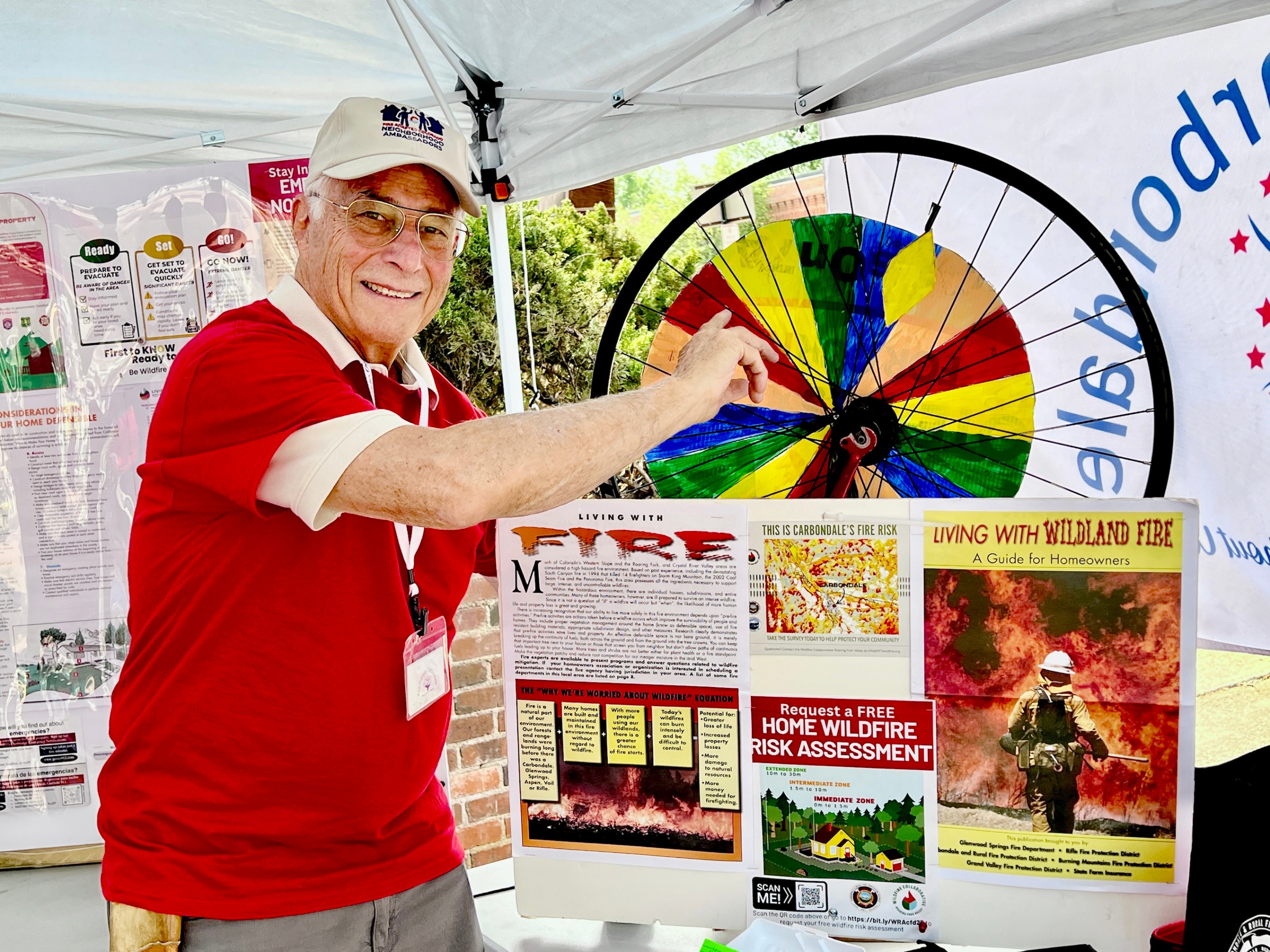 Age-Friendly Carbondale Treasurer Ted Zislis spins the wheel at a wildfire preparedness booth on Friday, July 3. Look for the booth at future First Fridays and the Wednesday Carbondale Farmers Market. Photo by Amy Hadden Marsh